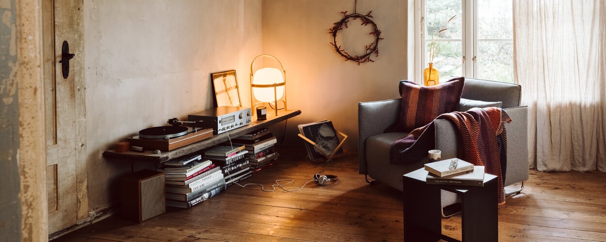 A cozy living room with soft lighting, featuring an armchair, a sideboard, and other furniture