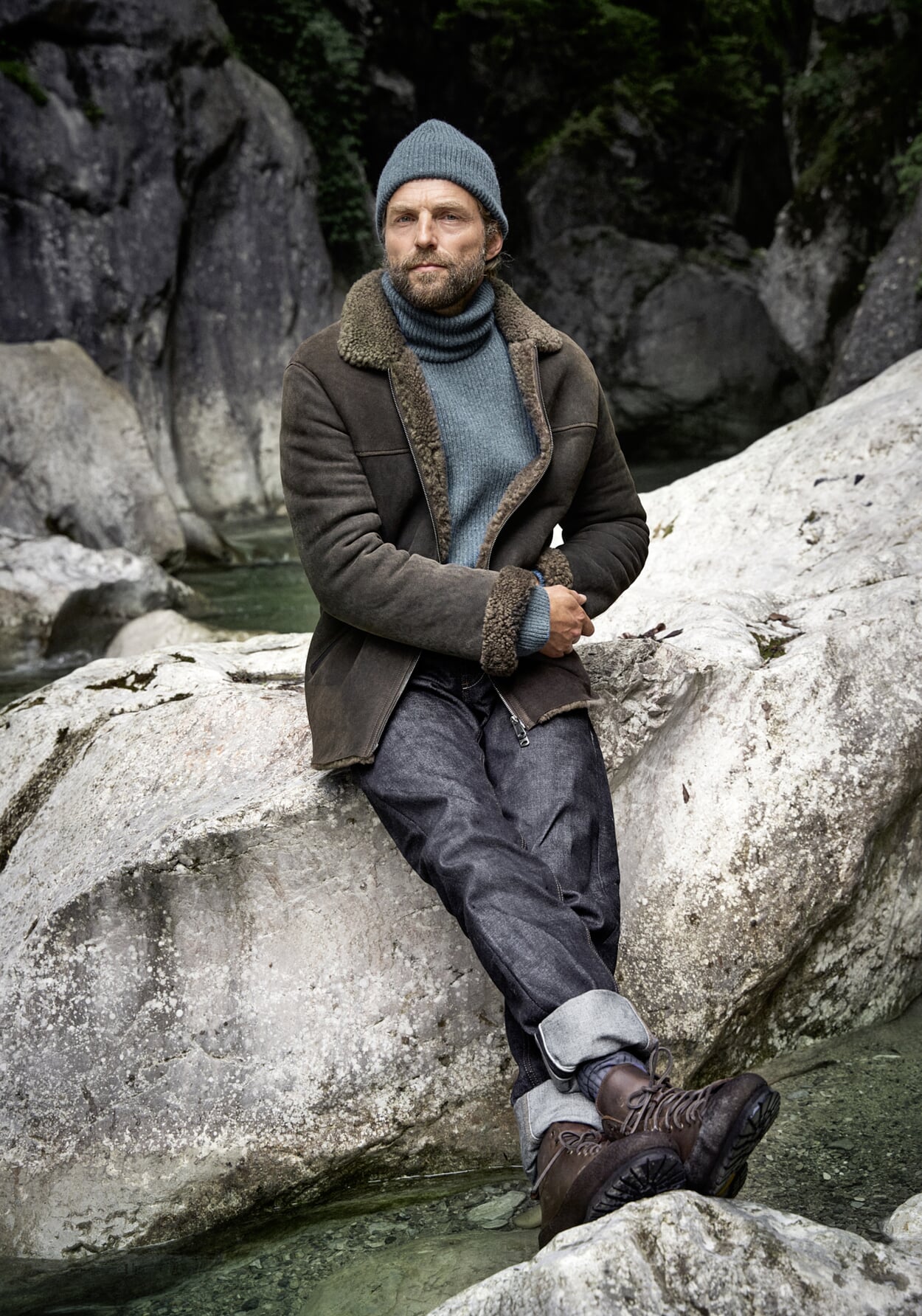 Man in herfstoutfit voor grijze rotswand