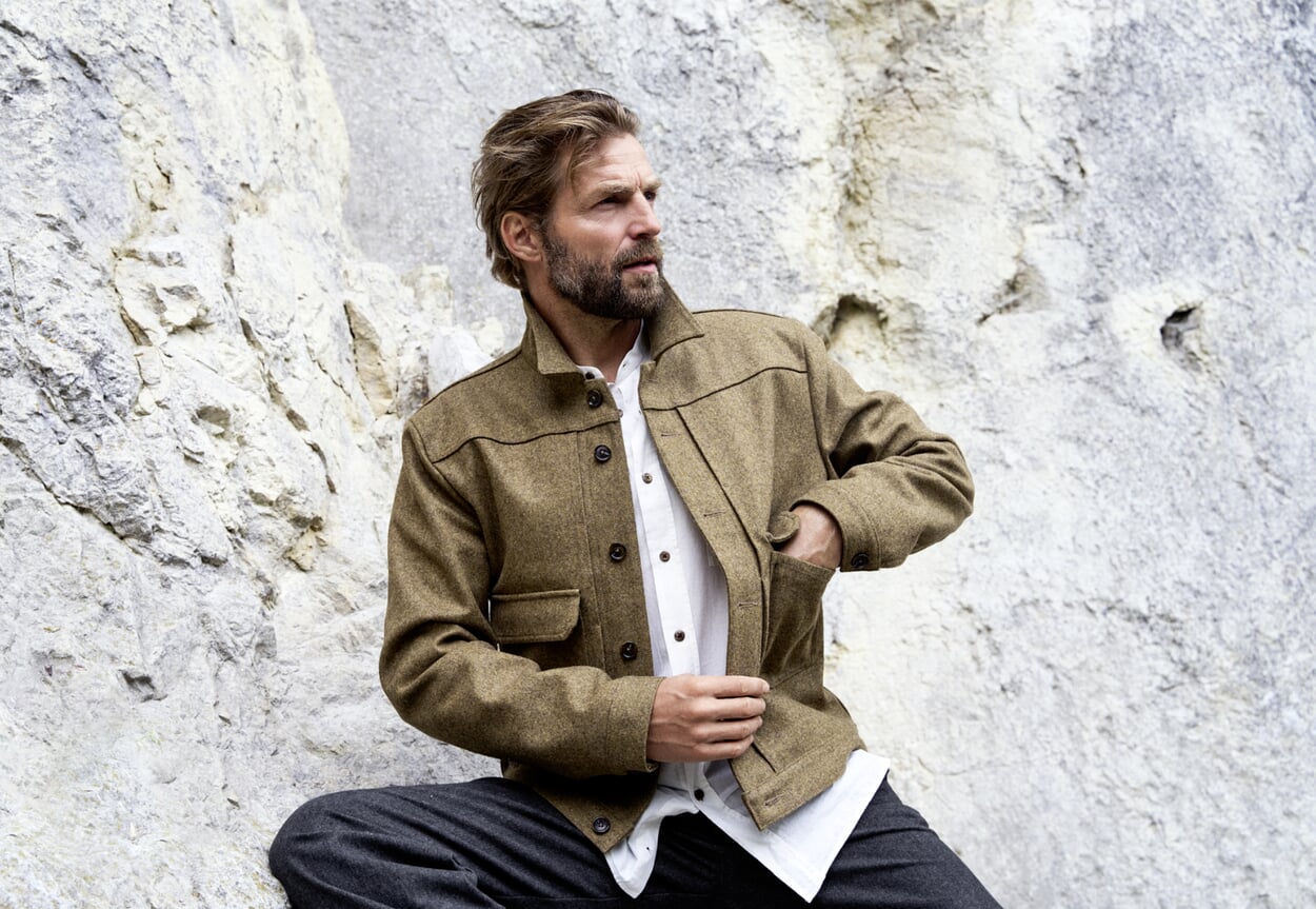 Man in herfstlook voor grijze rotswand