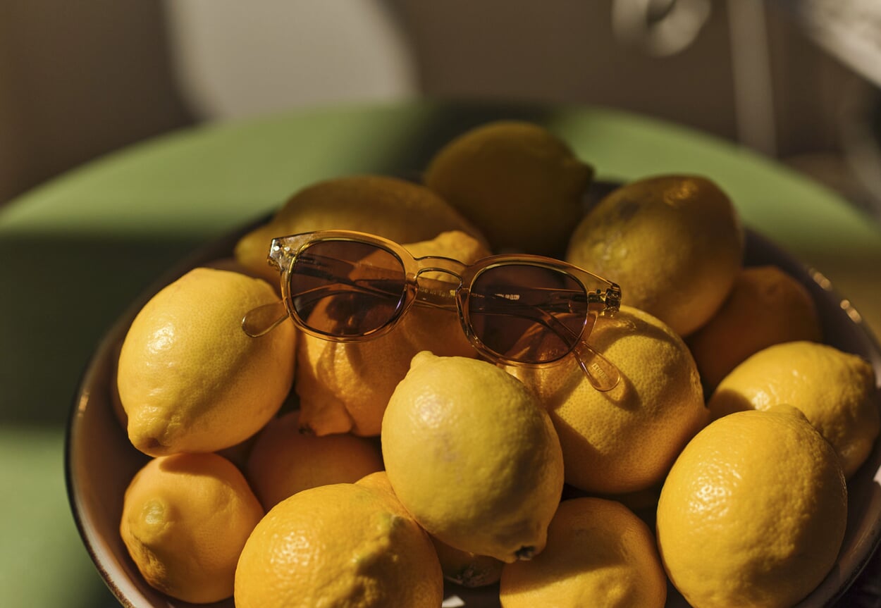 Sonnenbrille auf Zitronen und ein Model im Frühlingsoutfit in Abendsonne